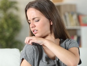 Photo image of a teen girl looking concerned and scratching her shoulder.